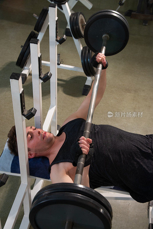 肌肉强健的健美运动员在健身房的卧推举重。