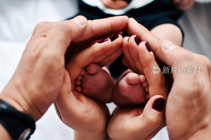 一个新生儿的脚在父母的手中。幸福的家庭oncept。爸爸妈妈抱着宝宝的腿