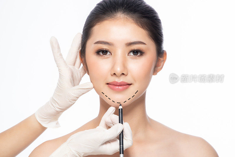 脸部线条，特写，整形外科概念，医生戴着手套的手在病人脸上留下痕迹。亚洲美女在美容院。整形外科诊所。