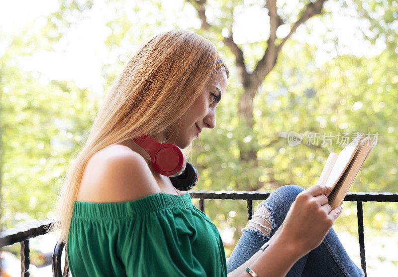 一位可爱的年轻女子在美丽的户外阅读一本引人入胜的小说