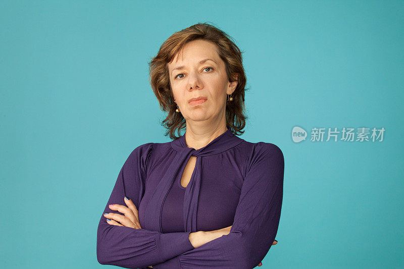 一个40岁的女人在蓝色的背景上穿紫色的衬衫的工作室肖像