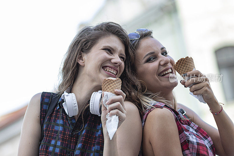 两个漂亮的年轻女人正在外面的公园里享用冰激淋