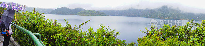 在雨和雾下，厄瓜多尔妇女看Cuicocha湖的全景图