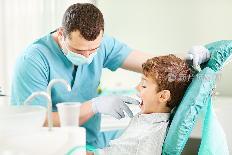 男孩和牙医正在对着镜子检查牙齿。