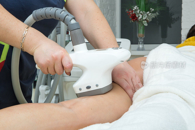 消除脂肪团的程序，在一个裸露的女性腿上使用反脂肪团的仪器纠正身体。