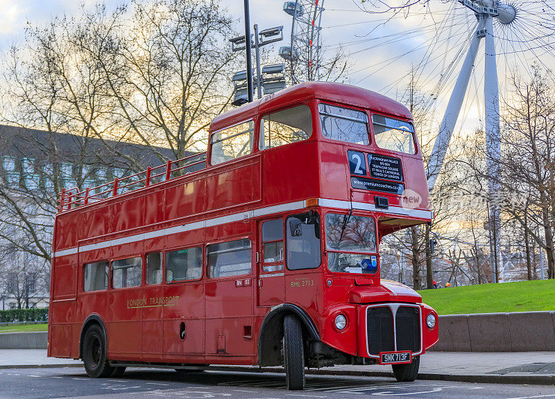 在英国伦敦市中心的伦敦眼前，著名的红色双层巴士“马路主人”行驶在一条空无一人的街道上