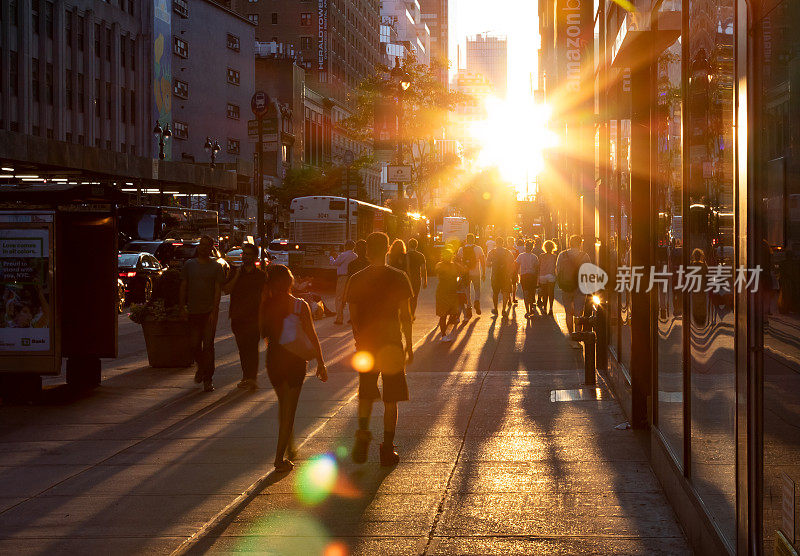 人群投下长长的影子，当他们走向明亮的夕阳在34街在纽约市