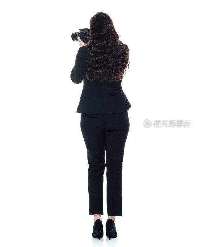 白人女摄影师站着，穿着职业装，拿着相机