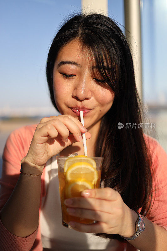 年轻女子在咖啡馆喝柠檬水