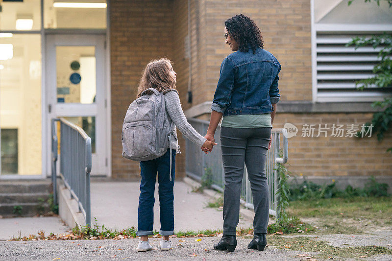 小学女孩牵着妈妈的手去上学