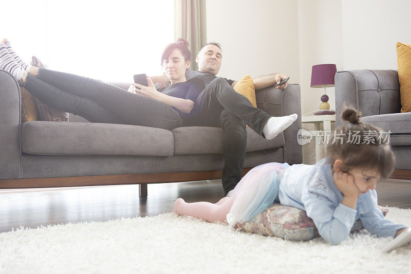 快乐的父母在沙发上休息，而孩子在使用数字平板电脑