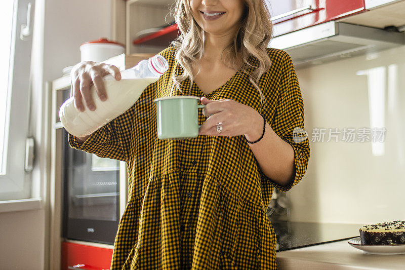 年轻女子在红色厨房里喝牛奶的特写