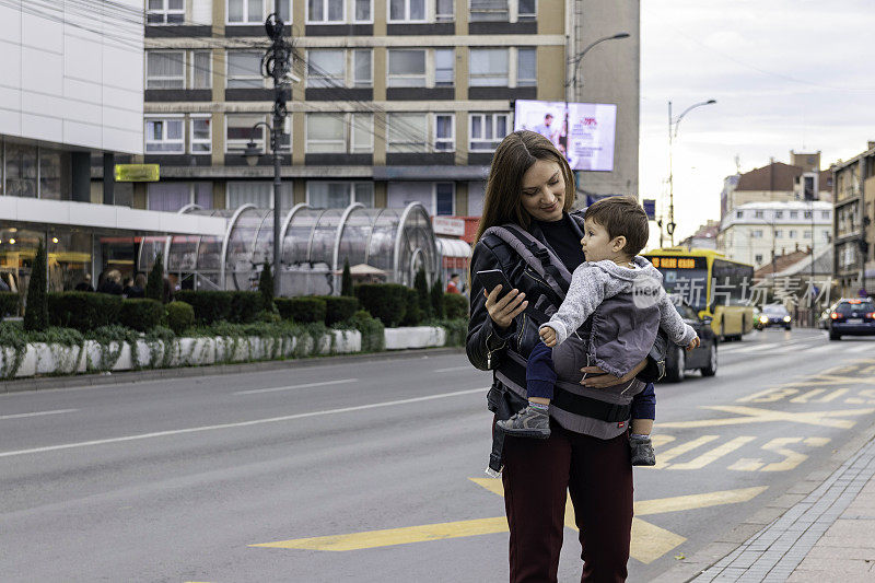 一个年轻女人带着儿子在街上等出租车