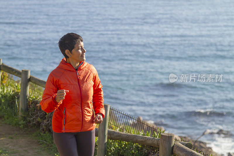 拉丁成年女子沿着海边的木板路跑步