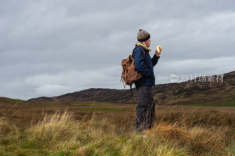 一个活跃的老人站在一个偏僻的地方，在一个阴天的冬天在苏格兰西南部