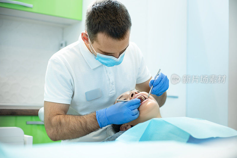 牙医在牙科诊所检查年轻女子的嘴。