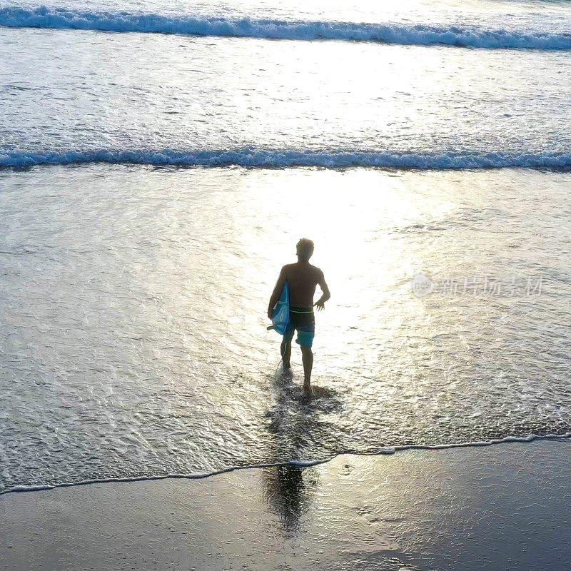 日出时分，一名男子带着冲浪板奔向太平洋