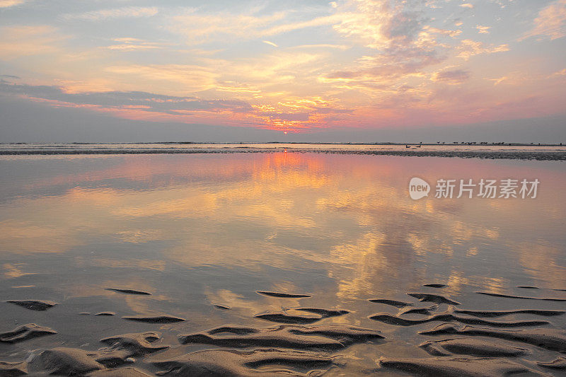 在平静的海面上，夏日日落时沙滩上的涟漪