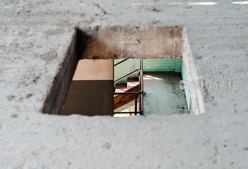 从地板上的洞可以看到废弃的工厂楼梯
