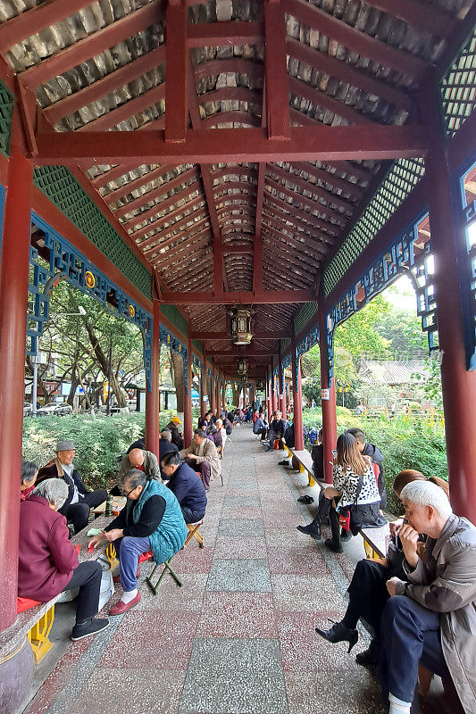 人们在成都街道公园的亭子里坐着聊天。