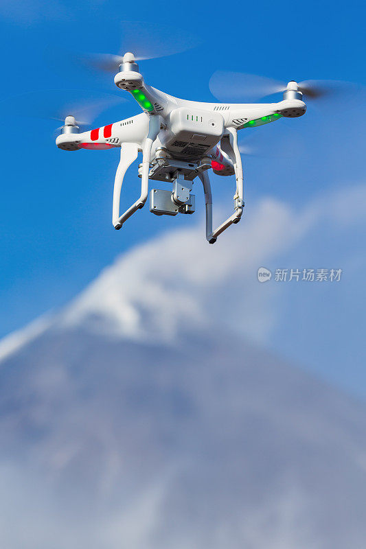 正在飞行的无人机无人机四轴飞行器在空中拍摄火山喷发背景。关注前景