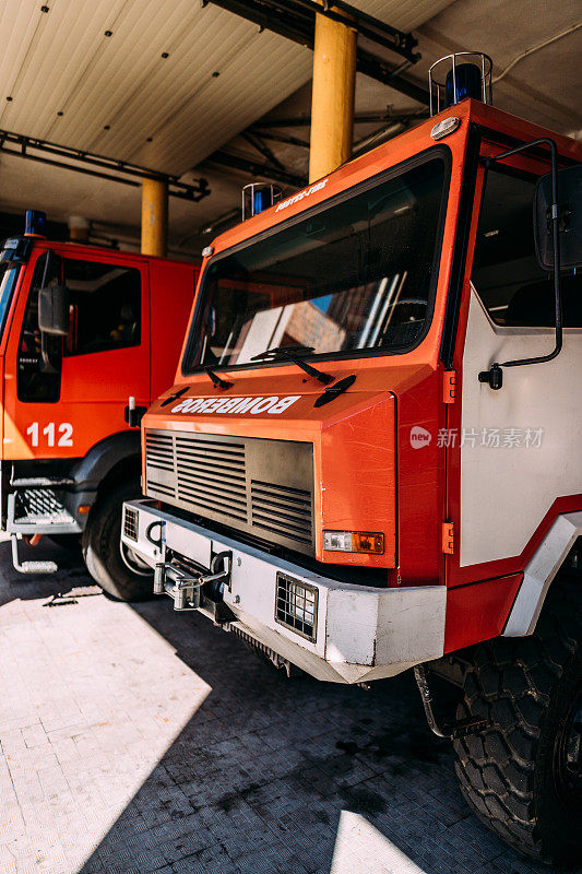 现代类似的红色前保险杠消防车蓝色报警灯和矩形前灯在车库与灰色地板在阳光