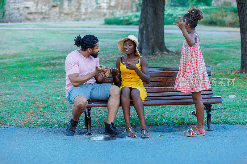 不高兴的非洲家庭坐在公园长椅上谈论问题。