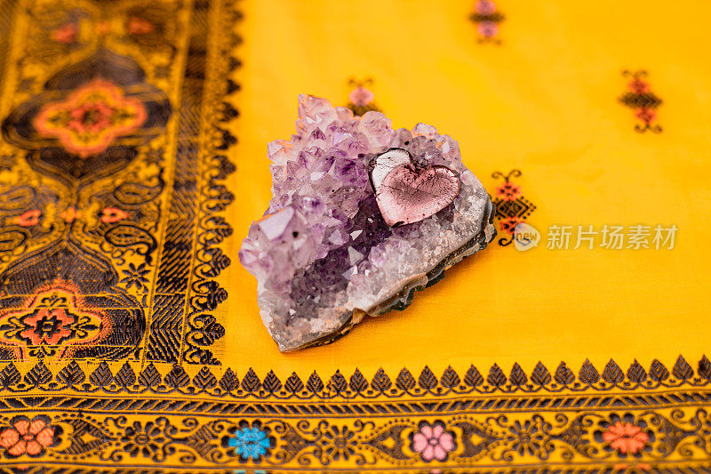 精神静物上面的紫水晶与一个心形的美丽的黄橙色印度编织纱丽