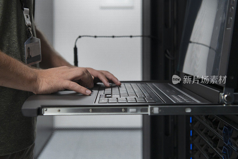接近数据中心工程师的手在超级计算机上使用键盘服务器室专家设施与男性系统管理员工作与数据保护网络的网络安全。