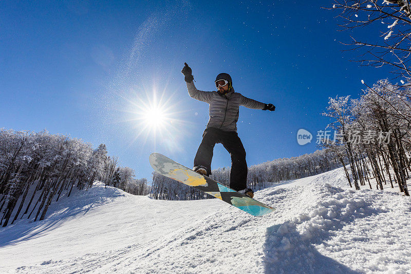 下图是男性单板滑雪运动员在雪地上玩花样。