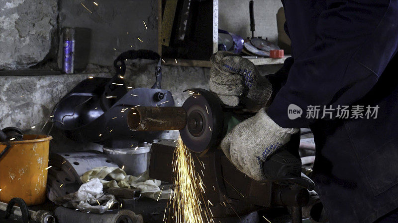 重工业工人用角磨机切割钢材，高速录像。框架。工人用角磨机和防护手套切割金属，产生热火花。