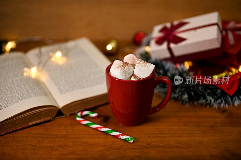 一杯热巧克力和棉花糖放在木桌上，有古董书和圣诞装饰