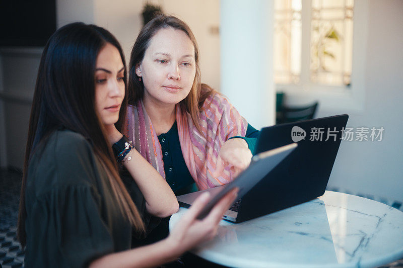 女企业家正在用笔记本电脑和平板电脑讨论她们的生意