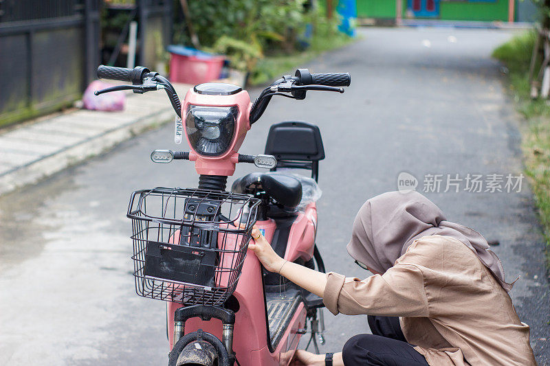 年轻的伊斯兰妇女在居民区骑电动自行车