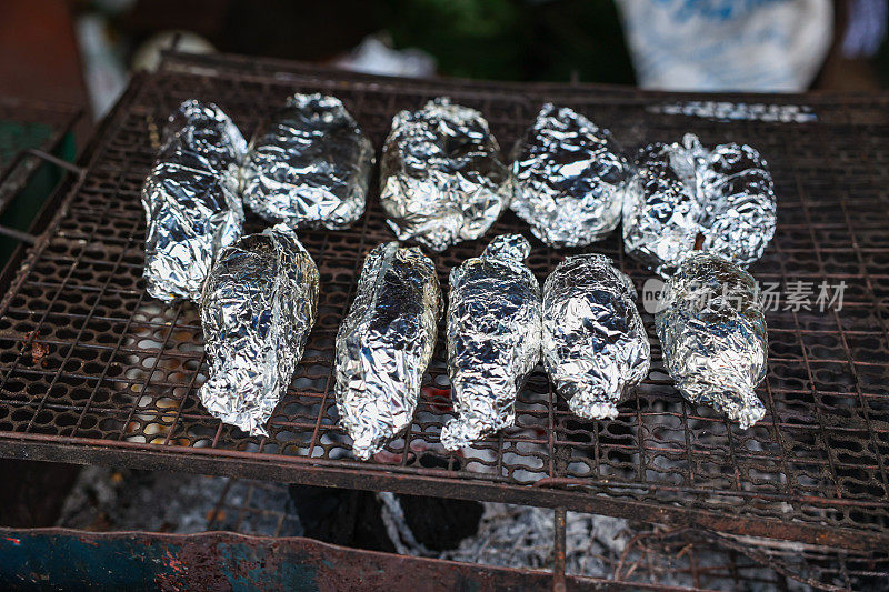 鱼或土豆用铝箔纸包裹在炭炉上烤