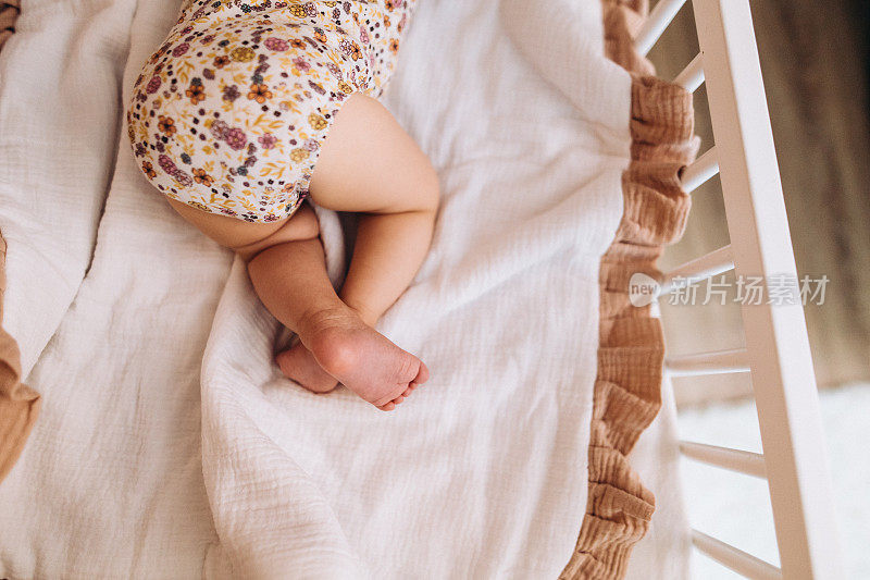 可爱的无法辨认的婴儿睡在婴儿床上