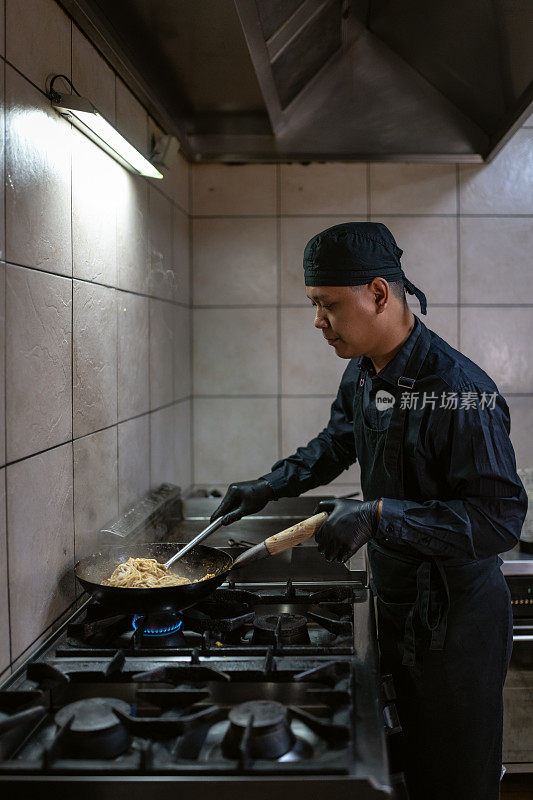 一个穿黑色制服的厨师正在准备饭菜。