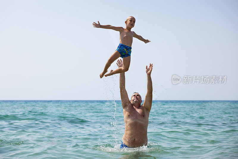 父亲把儿子抛向空中，同时一起在海里玩耍