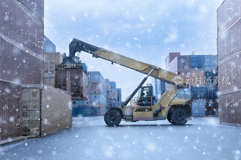 起重机在雪地上吊起堆场集装箱。