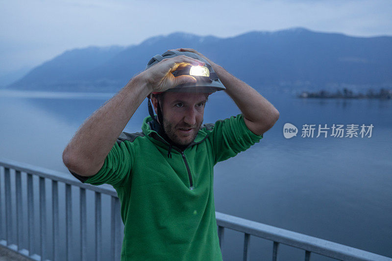 骑自行车的人调整头盔上的头灯，夜间户外健身