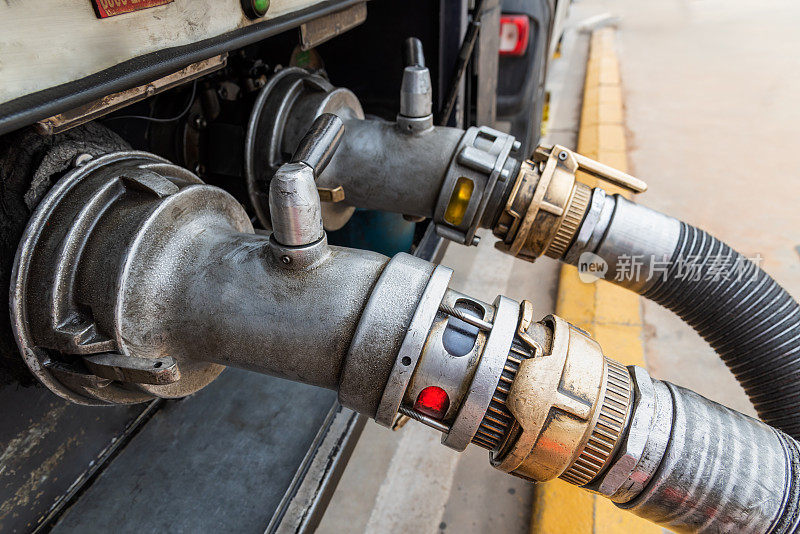 油罐车口连接排放软管的装置，在背景中排放补贴柴油(柴油B或红色)和正常柴油(柴油a)。