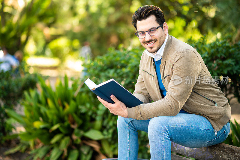 男学生在室外的长凳上看书