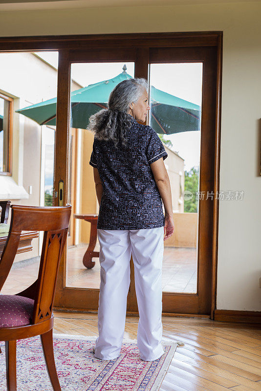 一位拉丁裔妇女在她从事清洁服务的房子里，她穿着工作人员的制服，正在做她的活动