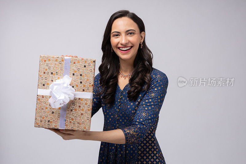 美丽的印度妇女穿着传统服装，拿着礼盒庆祝排灯节，孤立在白色背景的股票照片