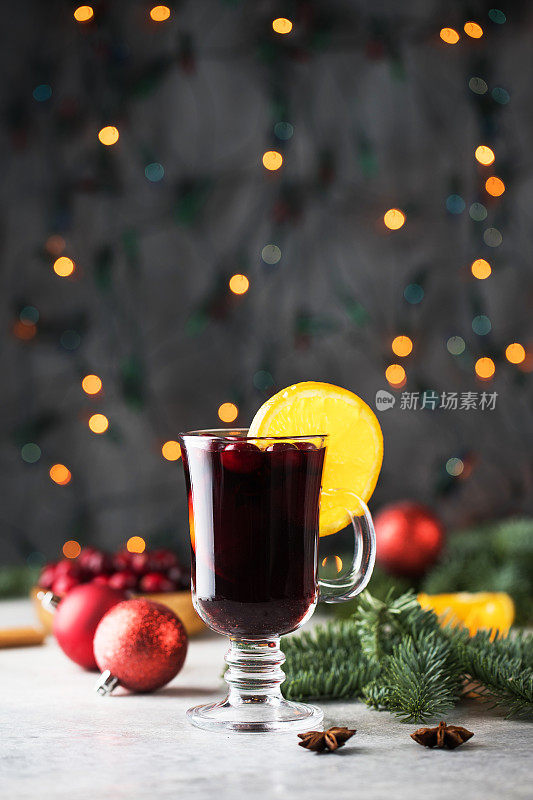 一杯热葡萄酒配上蔓越莓和肉桂棒，圣诞背景带散景。
