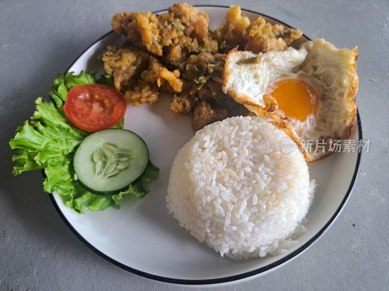 配米饭，鸡肉，单面煎蛋，生菜，番茄片和黄瓜片。食品菜单。