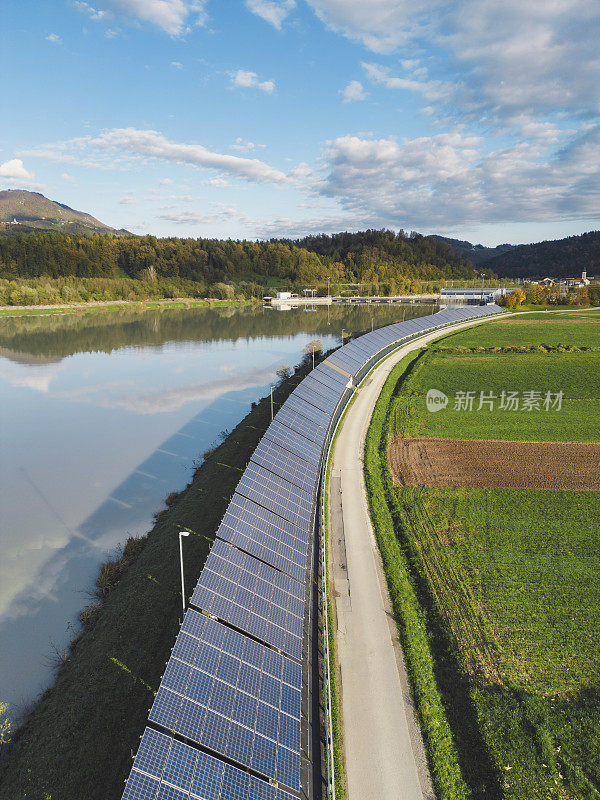 河边的一排太阳能电池板。一排排可持续能源太阳能电池板竖立在农田上。绿色能源与环境生态理念。