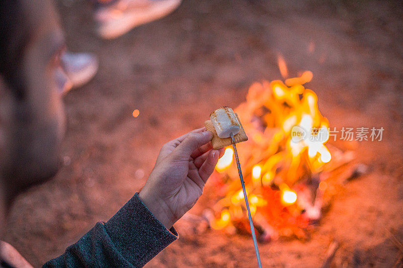 近距离的手拿着棉花糖和饼干做的S'more，在背景火