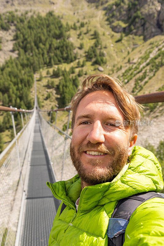 周末徒步旅行时，一名男子在山上的吊桥上自拍