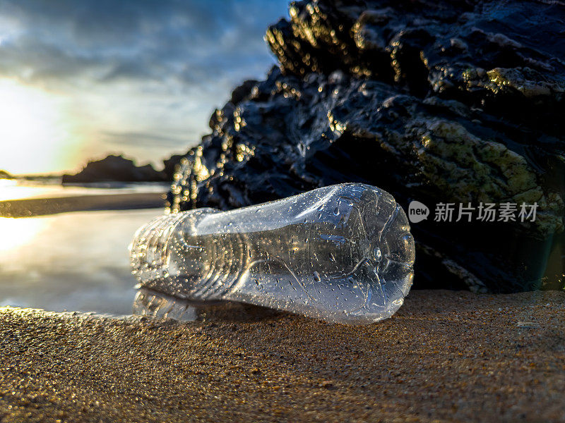 葡萄牙，日落时分，一个装满垃圾的空塑料瓶被遗忘在沙滩上